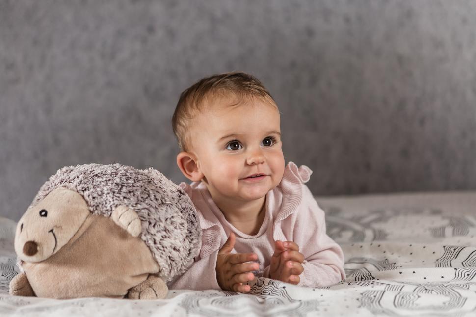 Free Image of baby lying on the bed with stuffed animal 