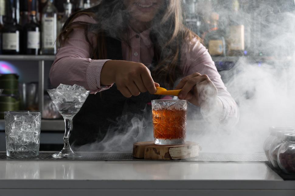 Bartender peels orange peel for cocktail at bar Stock Photo by