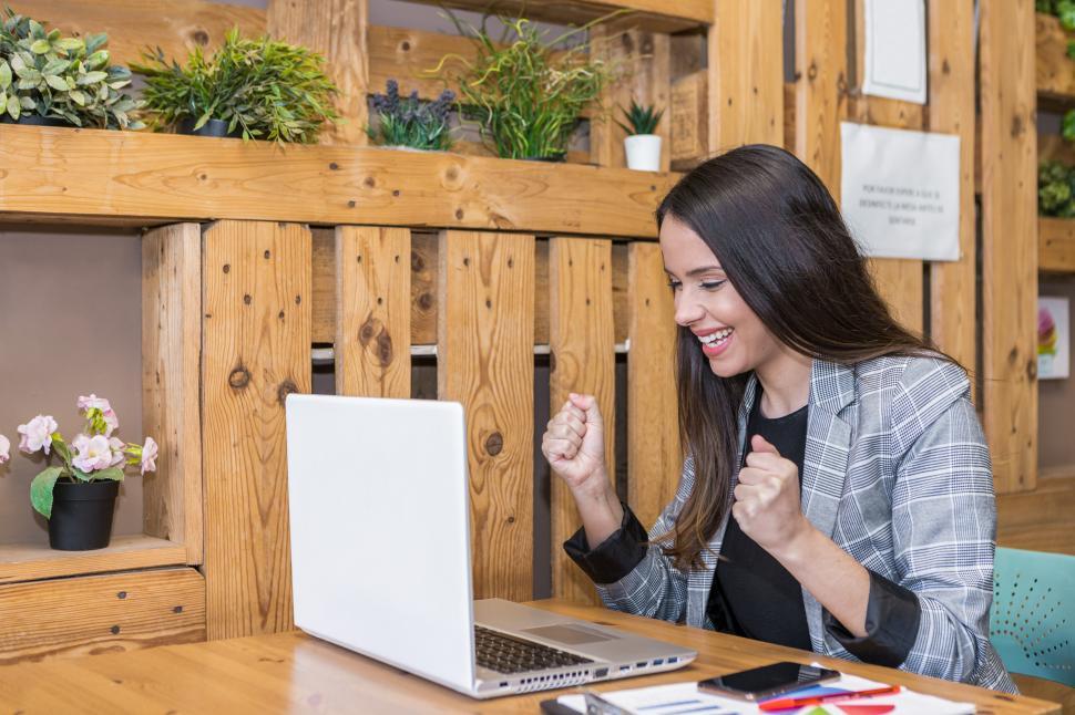 Free Image of Excited woman clenching fists while working on laptop 