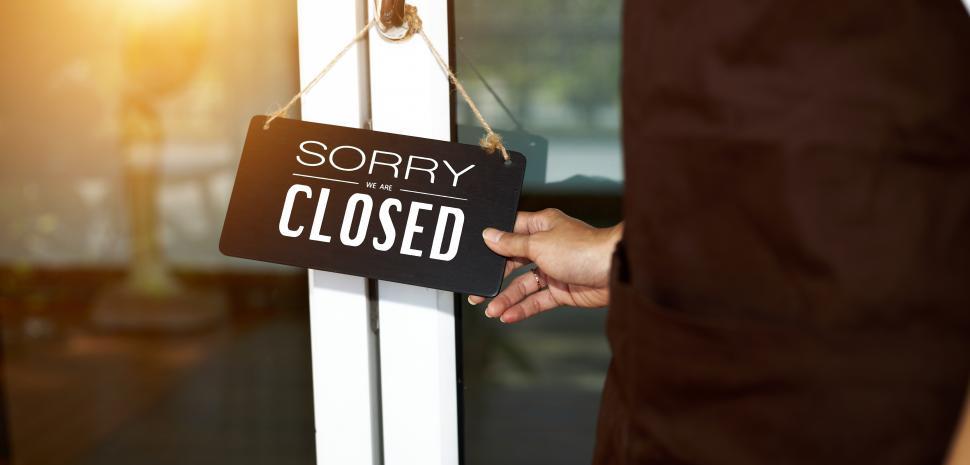 Free Image of Shopkeeper hanging a sign on the door - CLOSED, sorry 