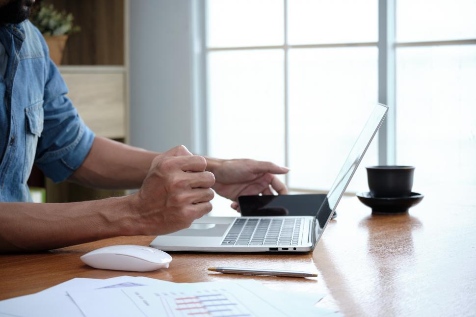 Free Image of Typing a keyboard on the laptop and holding a cellphone 