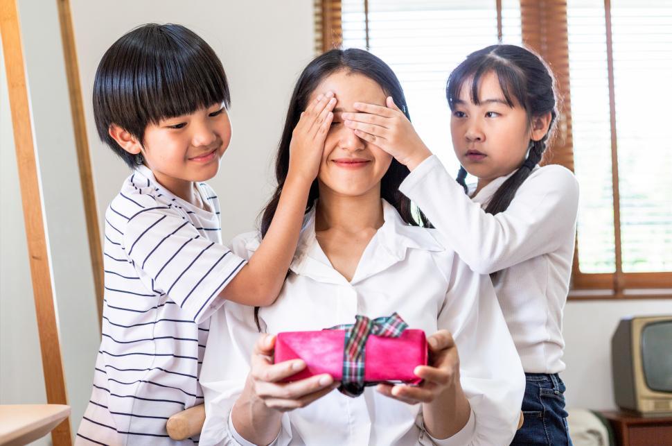 Mother's Day gift. Happy asian girl greeting young surprised mom, giving  her handmade card and wrapped gift box Stock Photo - Alamy