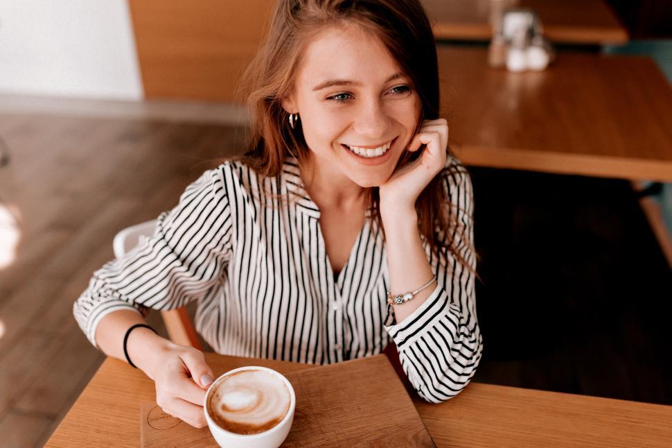 Free Image of Shot above of lovely cute girl in trendy blouse with a cup of coffee 
