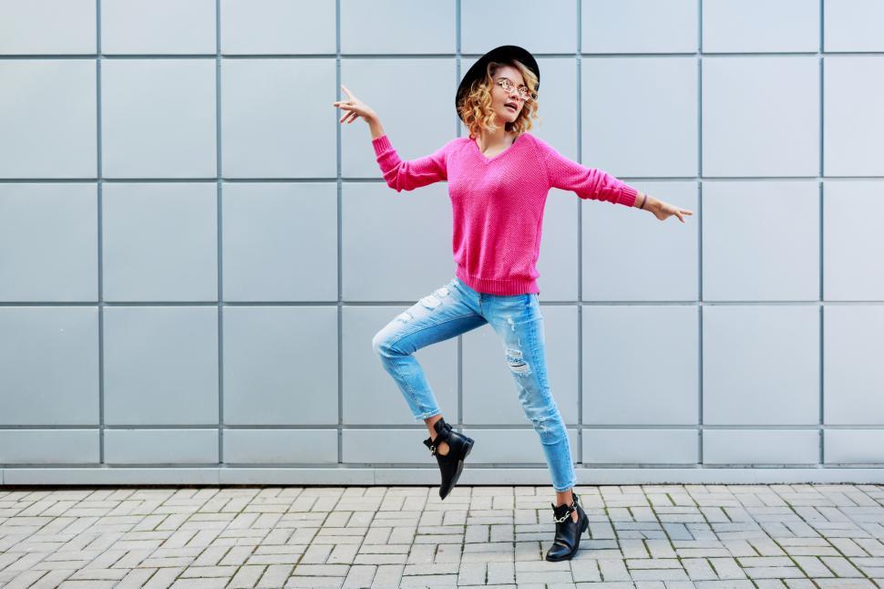 Free Image of Woman with wavy hairstyle posing on grey urban building wall 