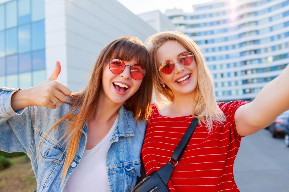 Free Image of Stylish positive women having fun and making self portrait on urban background. 