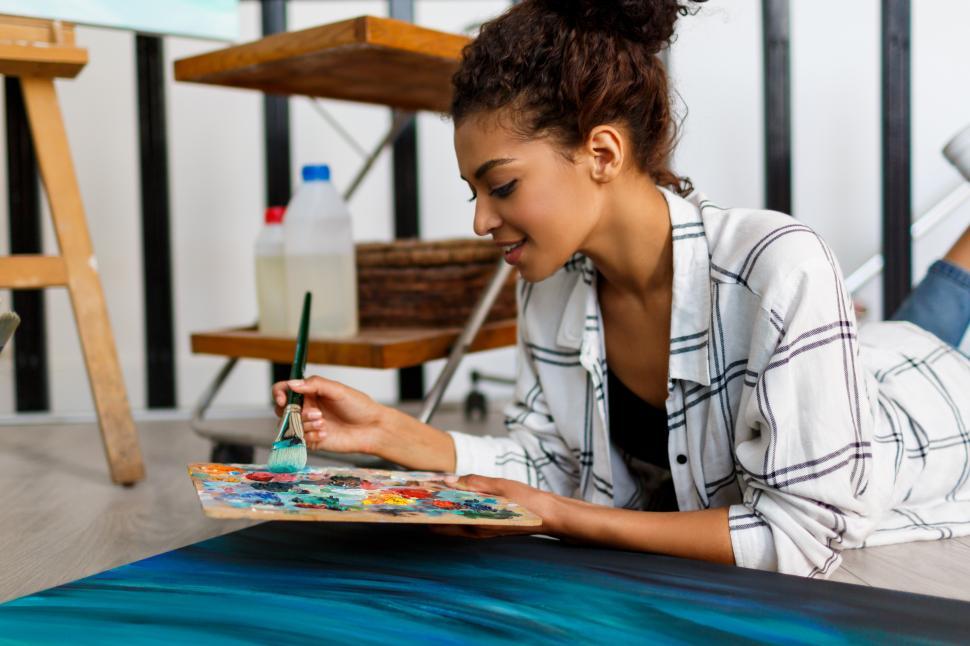 Free Image of Woman painter lies on the floor near  canvas and drawing 