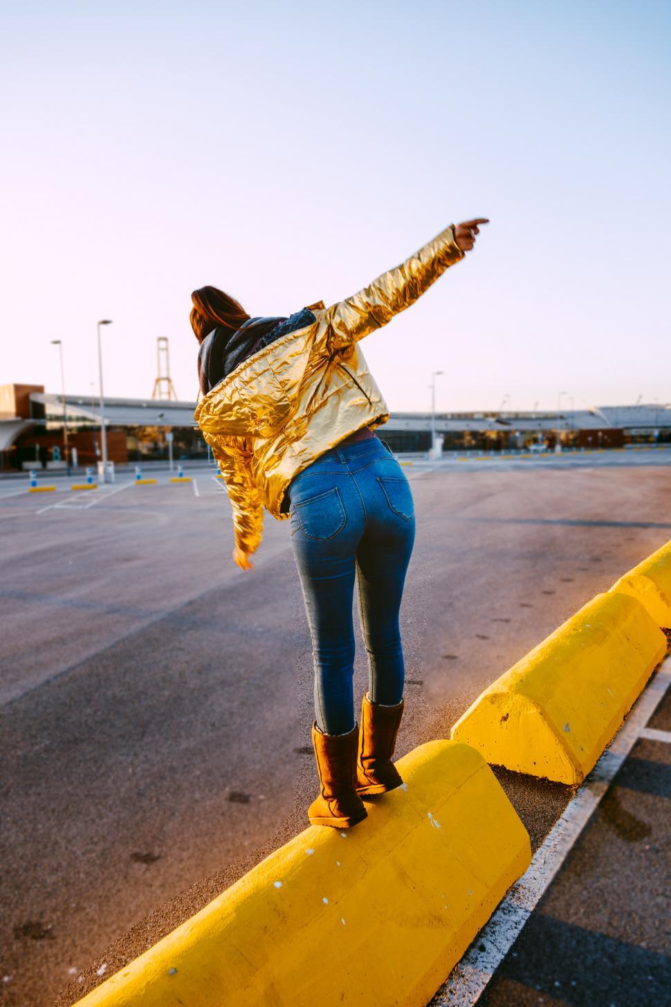 Free Image of an urban girl with a golden jacket in the sunset 