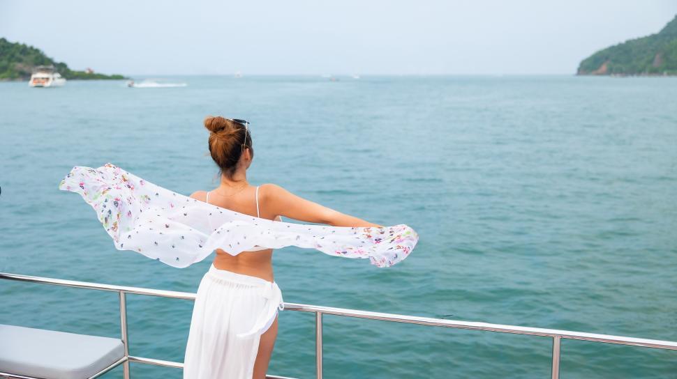 Free Image of Woman on vacation looks out over the water 