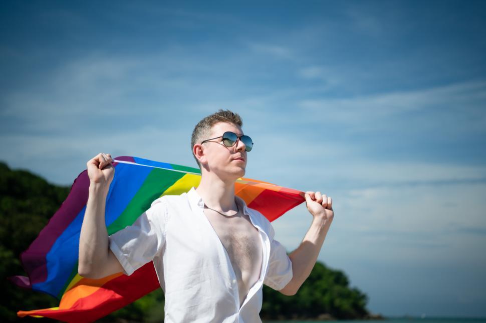 Young gay man holding a rainbow pride flag