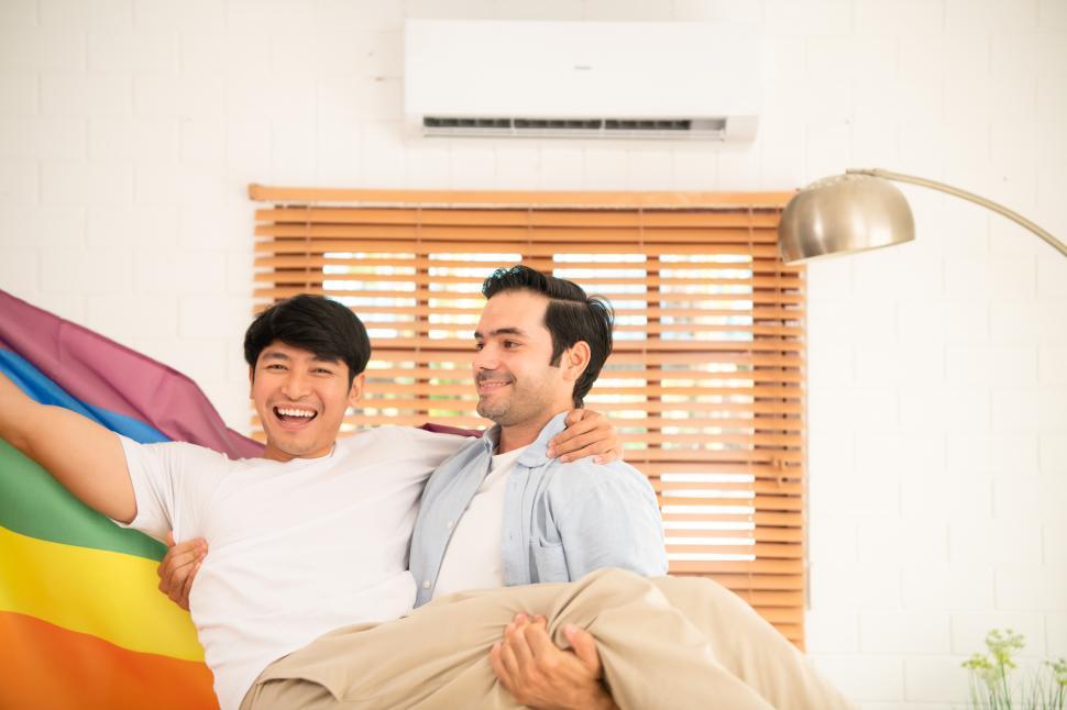 Free Image of Two happy men, one carrying the other, with Pride flag 