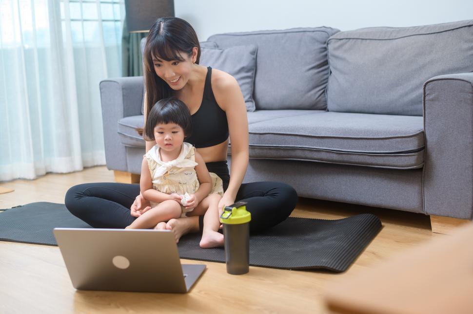 Free Image of Happy young woman in sportswear is with daughter exercising in living room 
