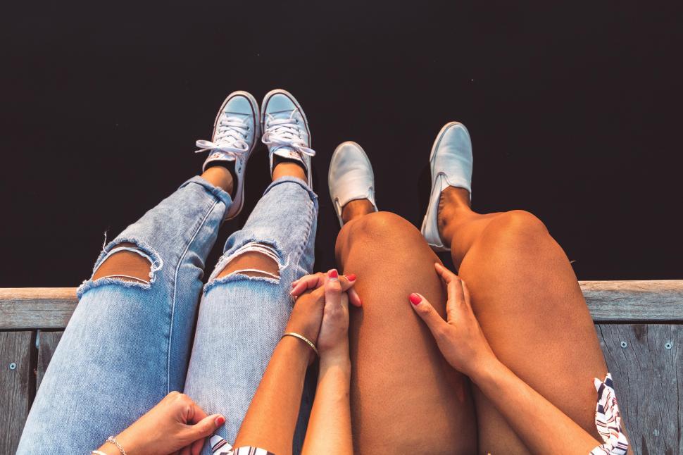 Free Image of Photo of two women sitting on a bench with crossed legs 