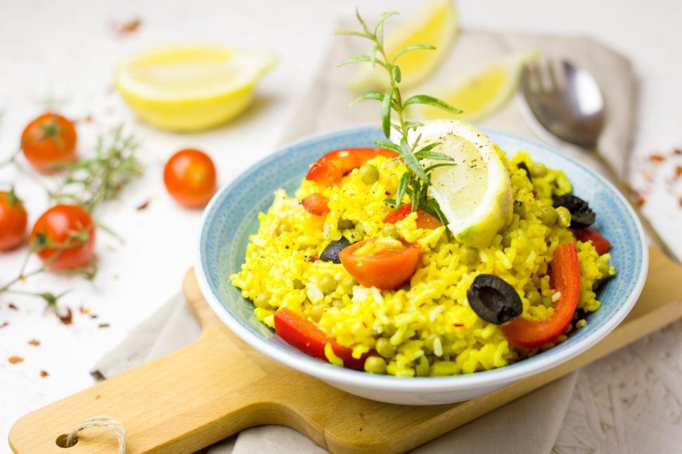 Free Image of A bowl of rice with vegetables and lemon on a wooden board 