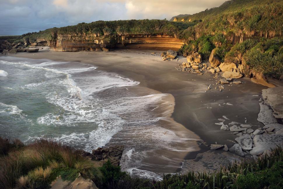 Free Image of A beach with waves crashing on the shore 