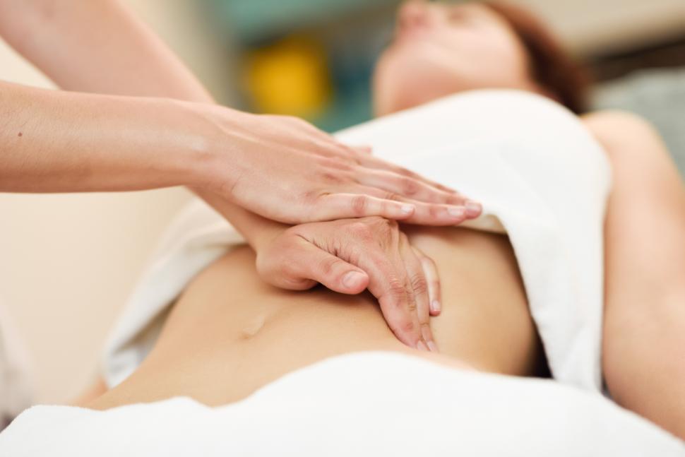 Professional female physiotherapist giving shoulder massage to blonde woman  stock photo