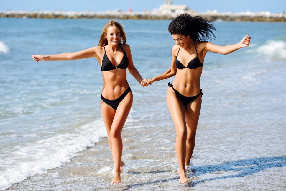 Free Stock Photo of Two young women with beautiful bodies in swimwear on a  tropical beach