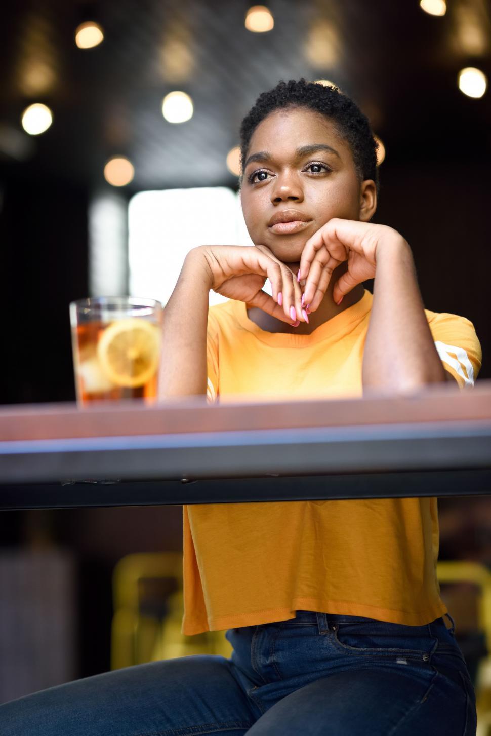 Free Image of Young black woman with very short hair taking a glass of cold tea. 