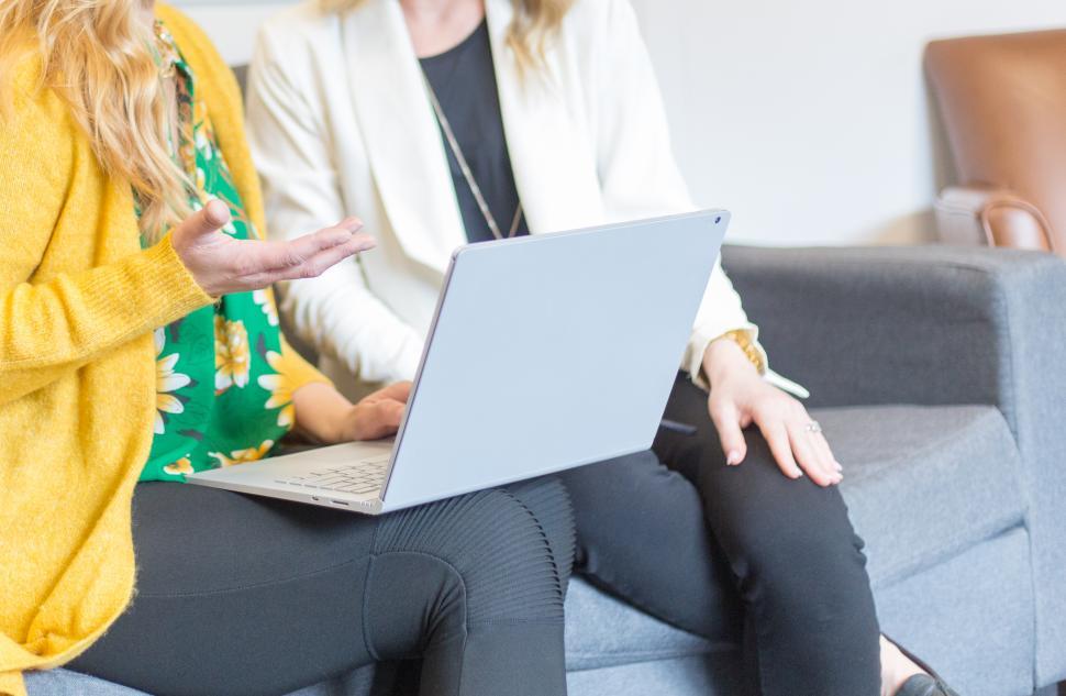 Free Image of A woman sitting on a couch with a laptop 