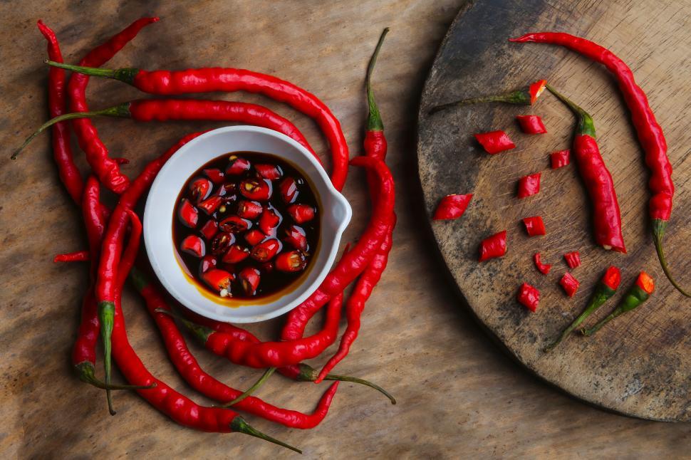 Free Image of A bowl of sauce next to red peppers 