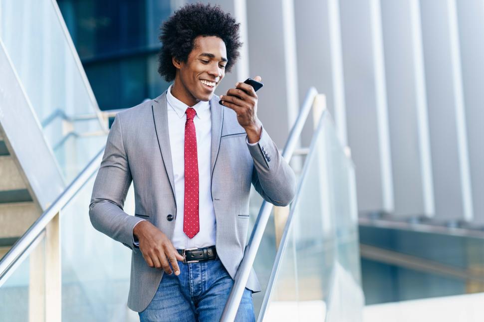 Free Image of Black Businessman using a smartphone near an office building 