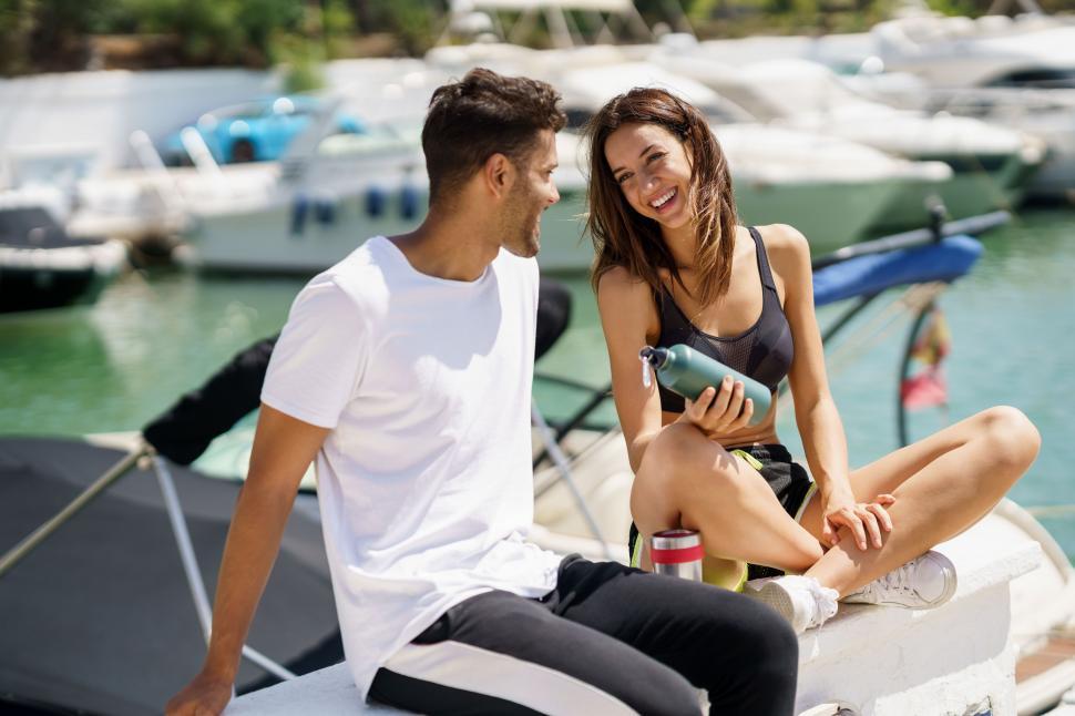 Free Image of Young sporting couple hydrate themselves with water in metal cans while taking a break after sport. 