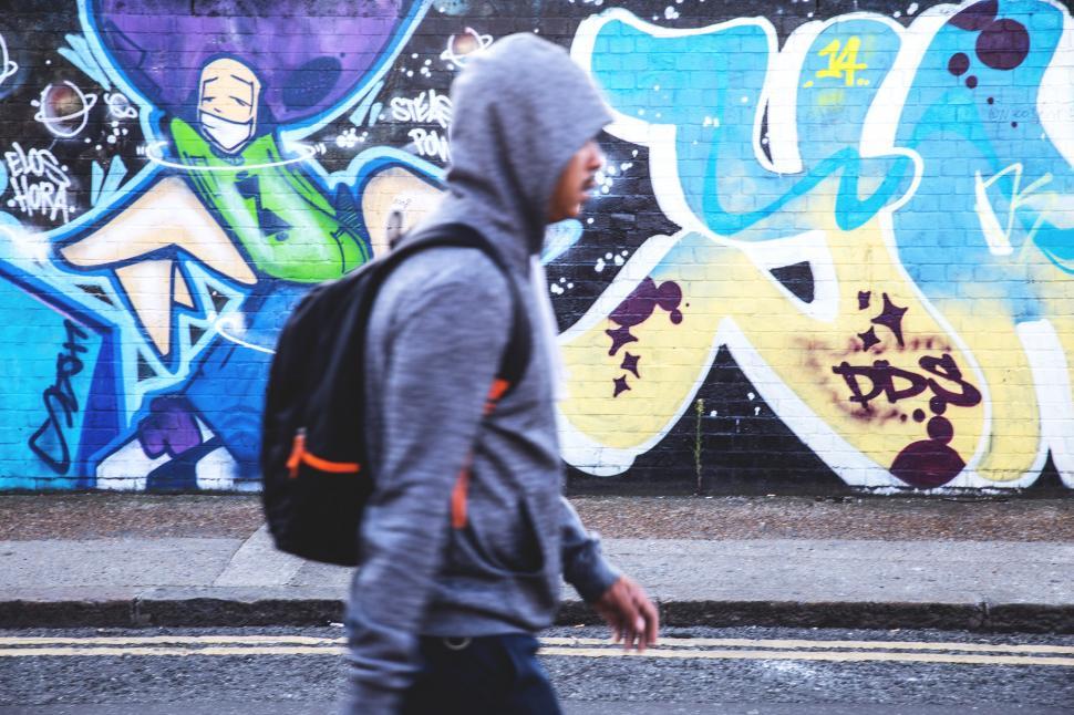 Free Stock Photo Of A Man Walking In Front Of A Wall With Graffiti 