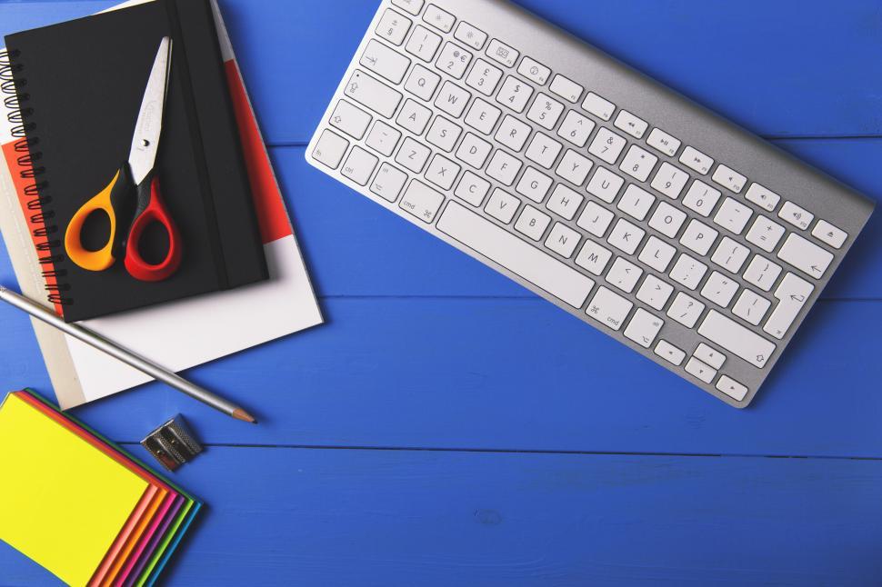 Free Image of A keyboard and stationery on a blue table 