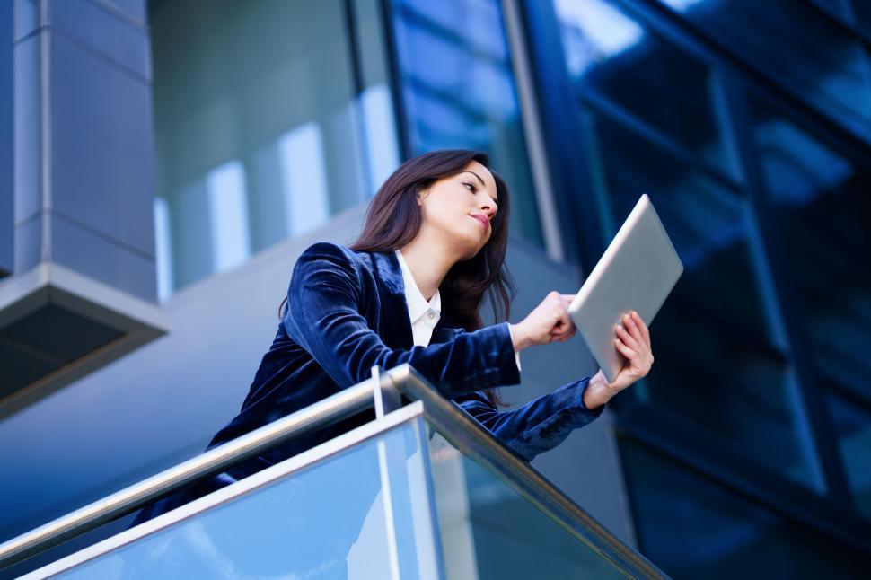 Free Image of Business woman wearing blue suit using digital tablet in an office building. 