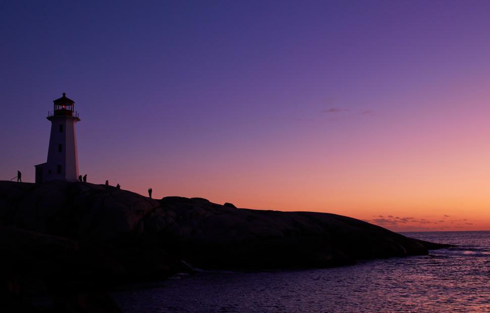 Free Image of A group of people standing on a rock by the water 