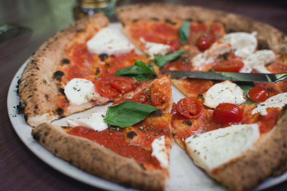 Free Image of A pizza with tomatoes and cheese on a plate 