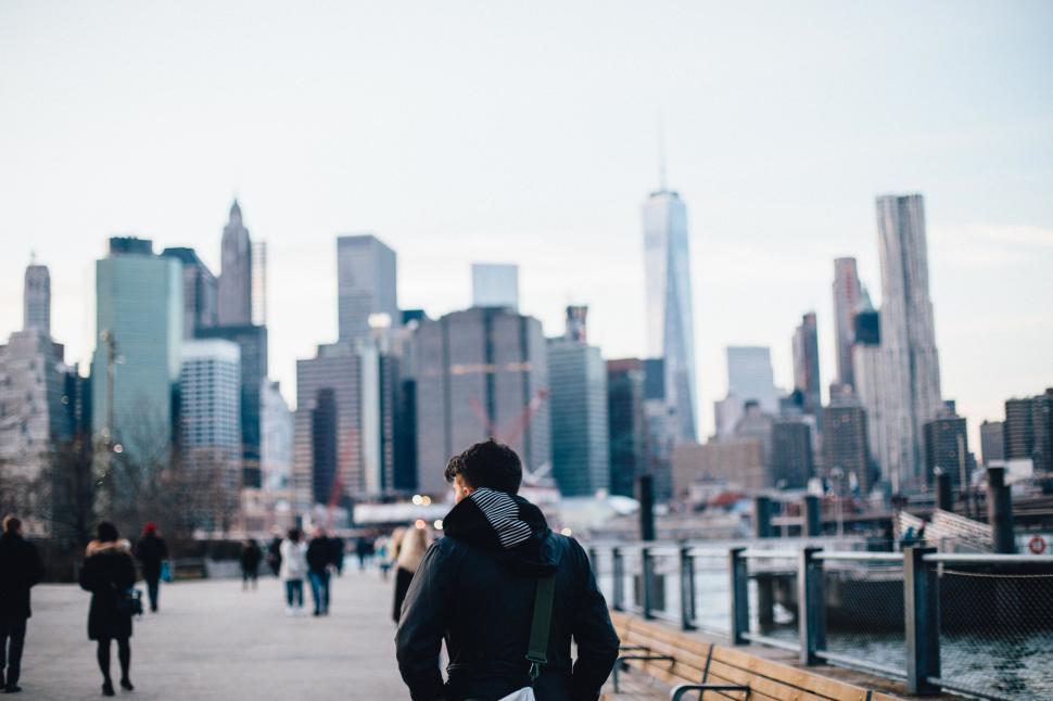 Free Image of A man standing on a bench in front of a city 