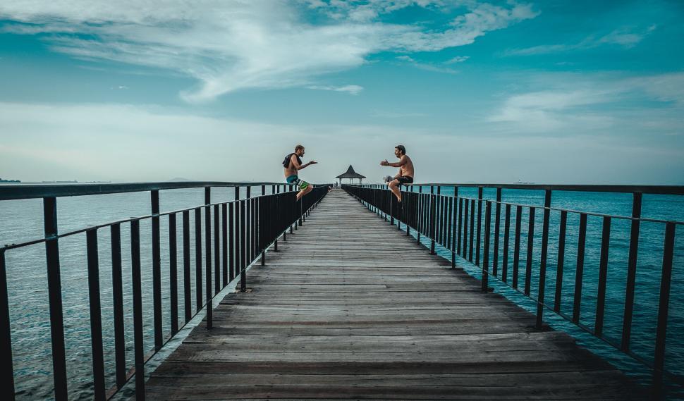 Free Image of Two men jumping off a bridge over water 