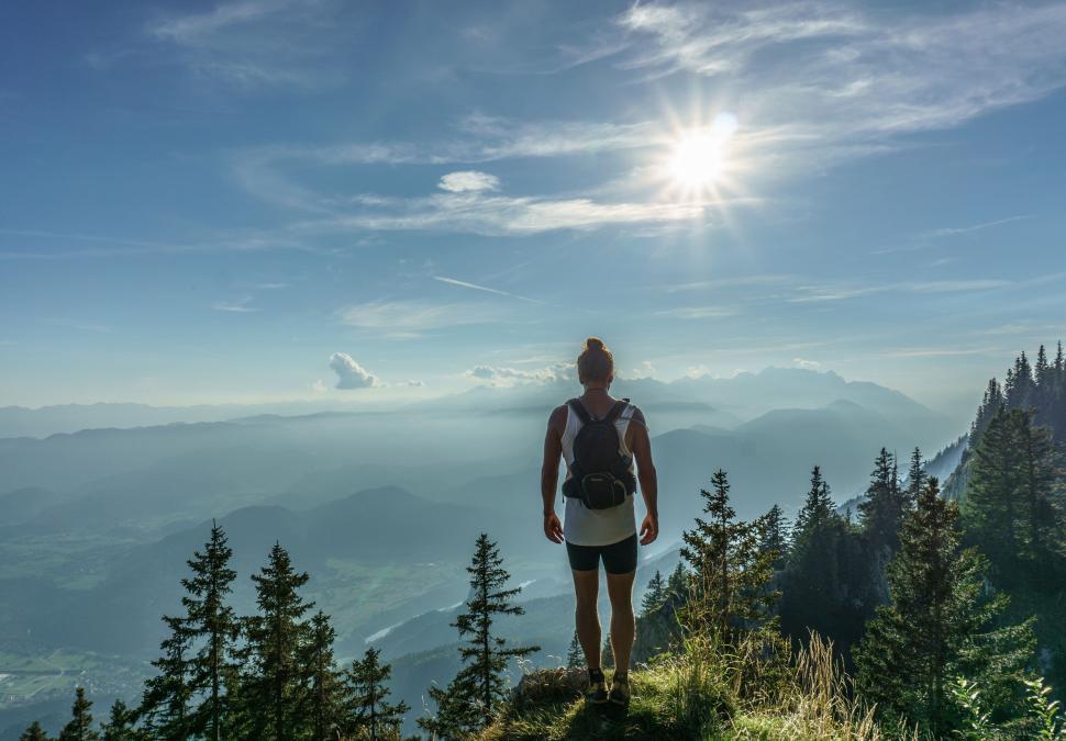 Free Image of A man standing on a cliff overlooking a valley 