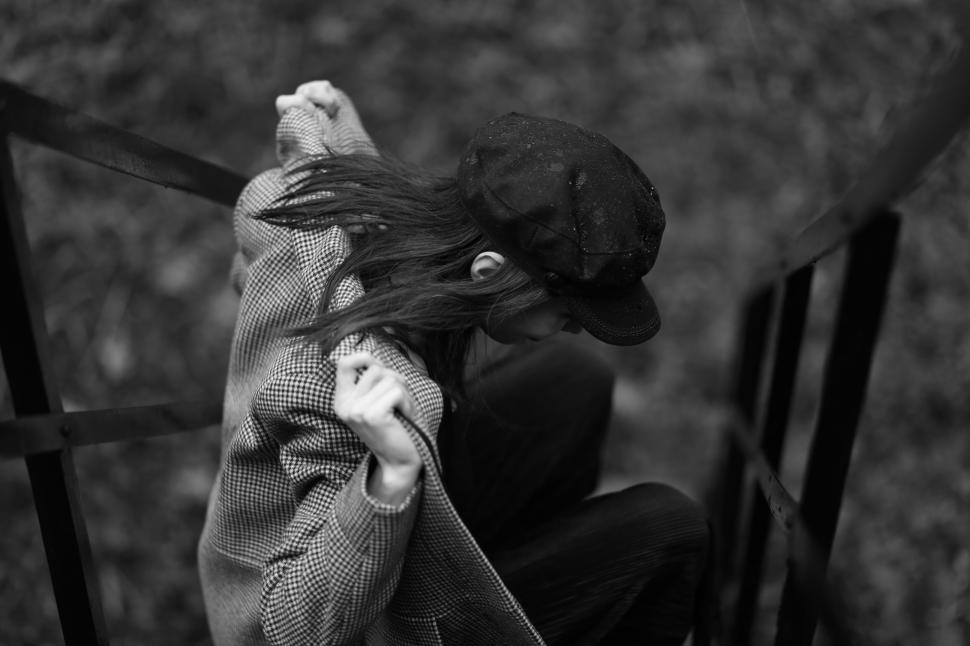 Free Image of A woman in a hat pulling her jacket off of a railing 