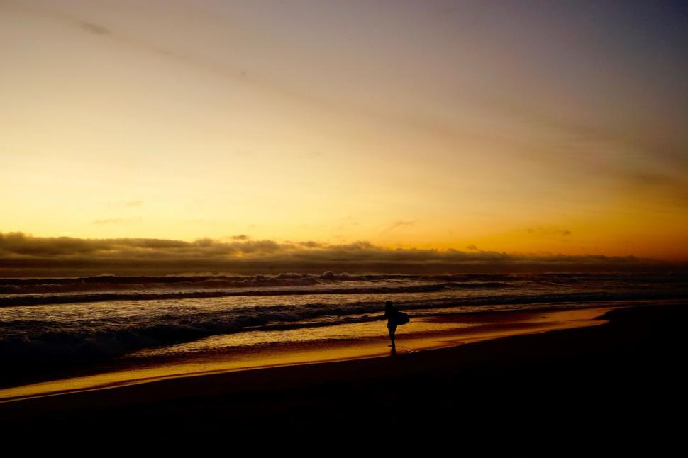 Free Image of A person carrying a surfboard on a beach 