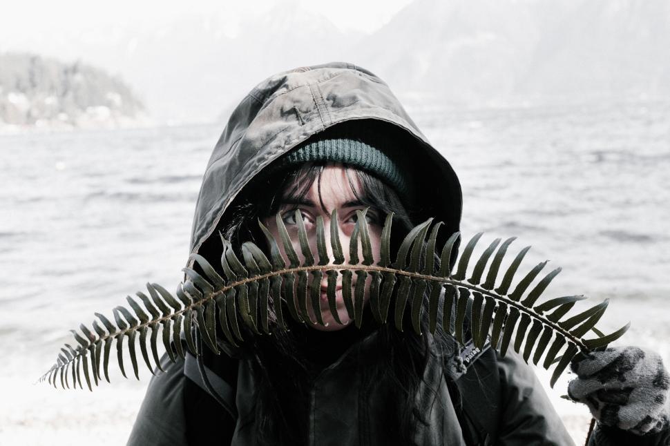 Free Image of A woman with a hood over her face with a fern leaf 