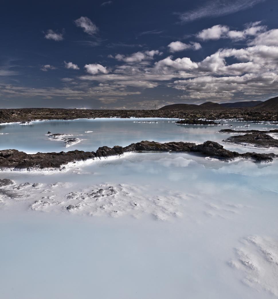 Free Image of A body of water with rocks and clouds in the sky 