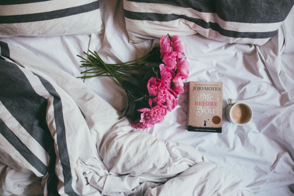 Free Image of A book and flowers on a bed 