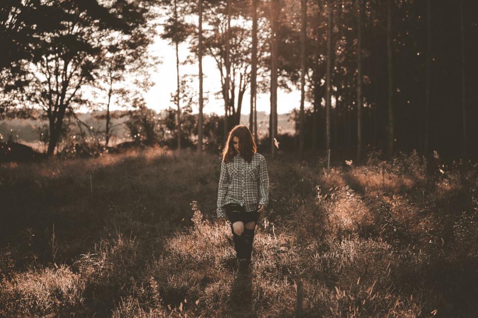 Free Image of A woman standing in a field with trees in the background 