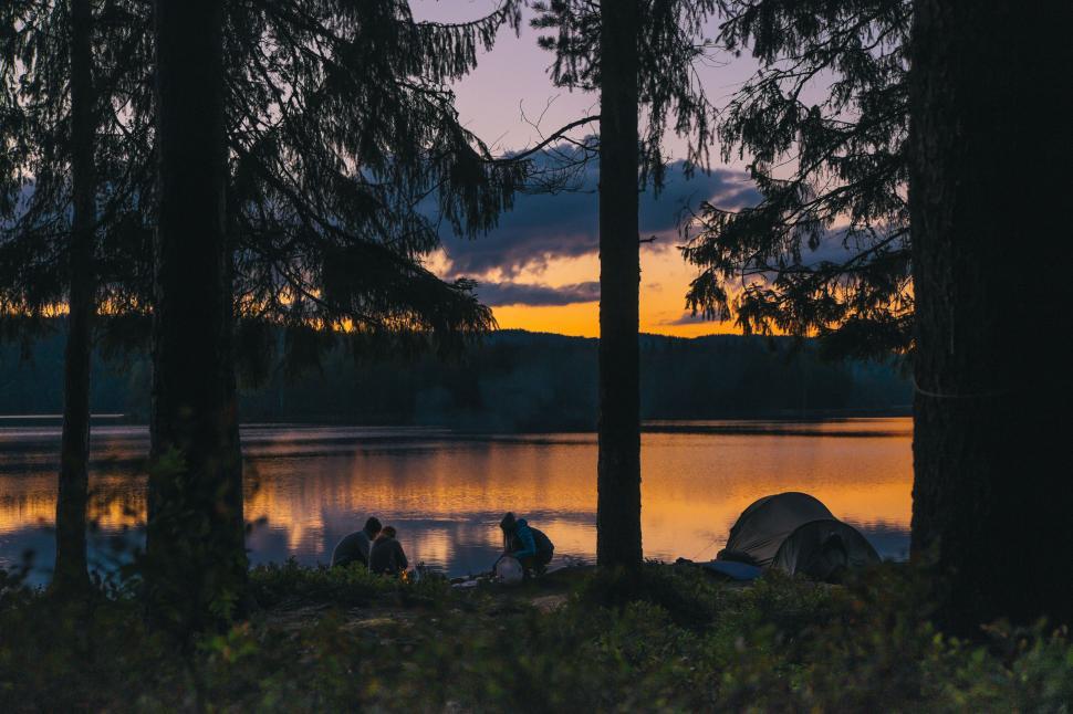 Free Image of People sitting on the shore of a lake with a group of people 
