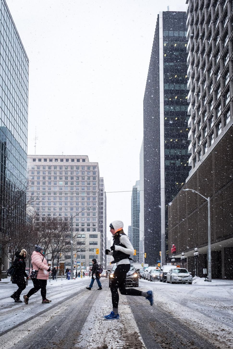 Free Image of A person running on a street in the snow 