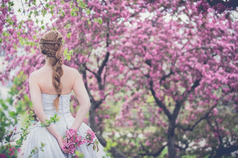 Free Image of A woman in a white dress with flowers in her hands 