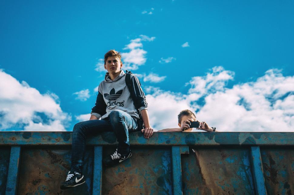 Free Image of A man sitting on a metal wall 