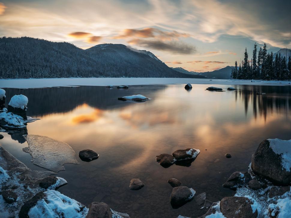 Free Image of A lake with rocks and trees in the background 