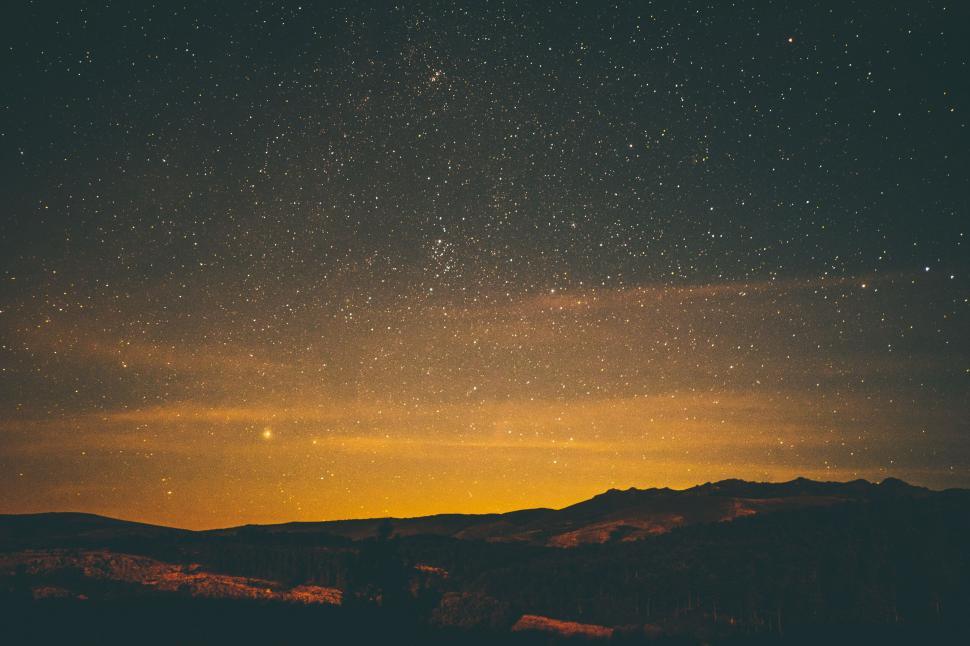Free Image of A starry sky over a mountain range 