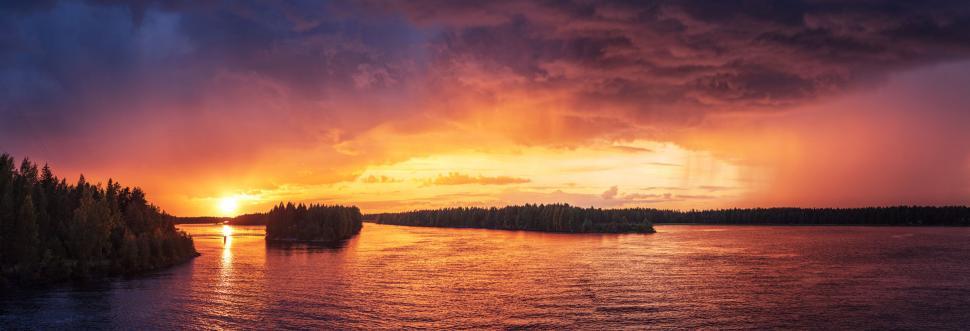 Free Image of A body of water with trees and a sunset 