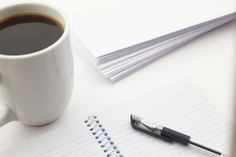 Free Image of A cup of coffee and a pen on a notebook 