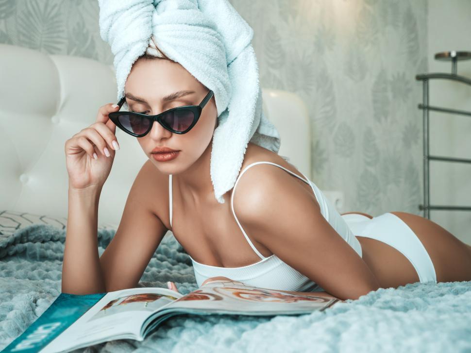 Free Stock Photo of A woman lying on a bed with a towel on her head and  sunglasses