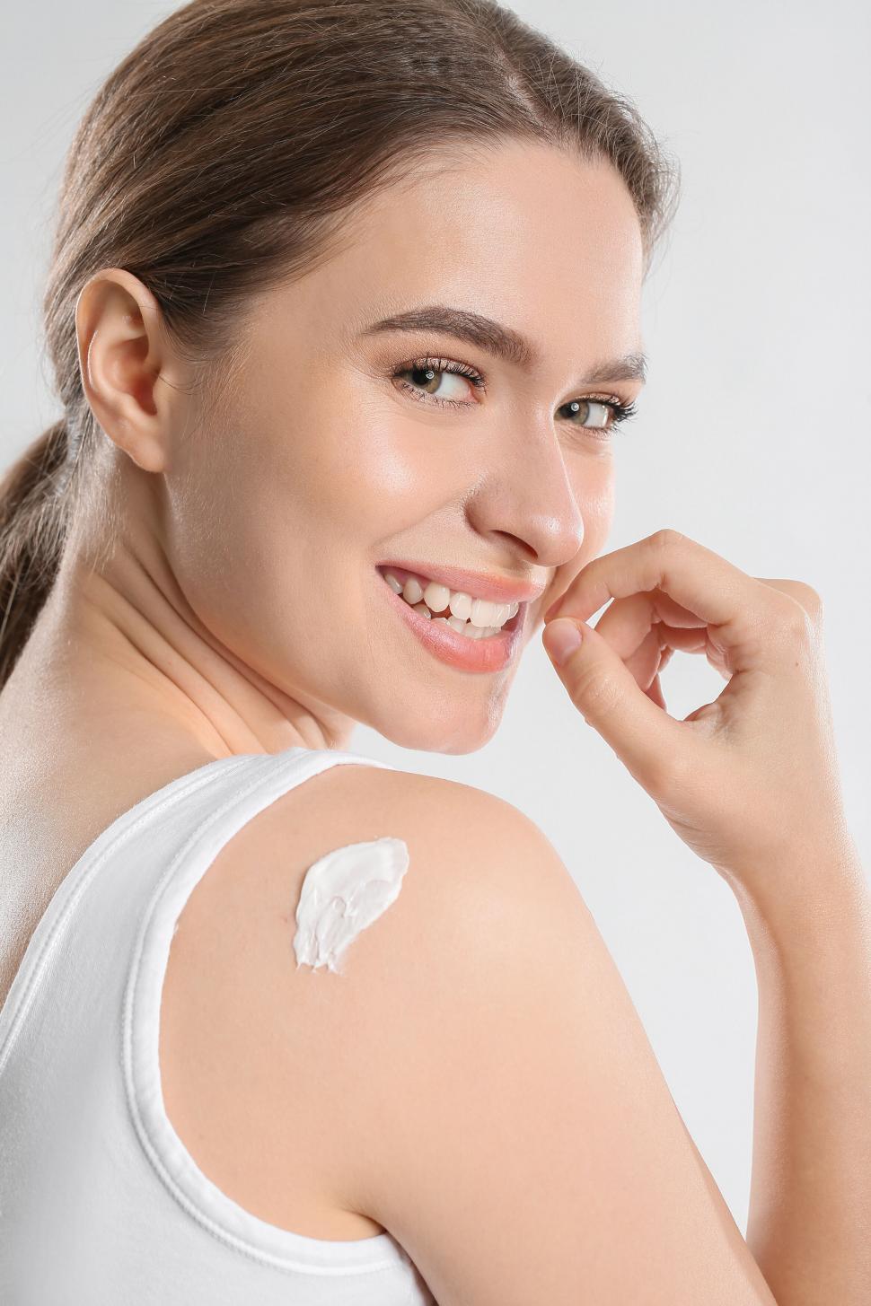 Free Image of A woman applying cream on her shoulder 