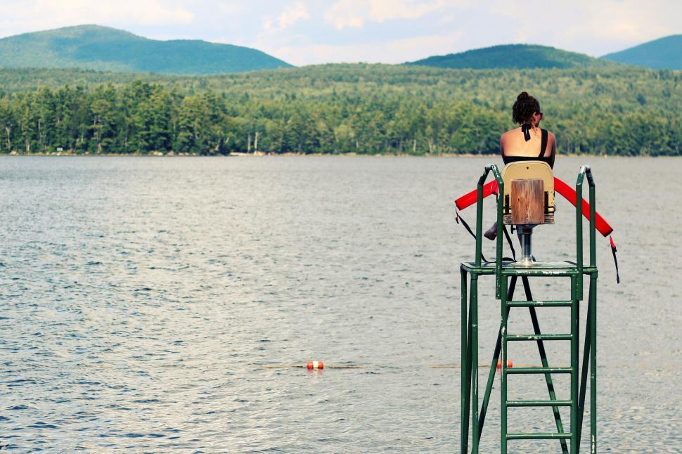 Free Image of A woman sitting on a platform in a lake 